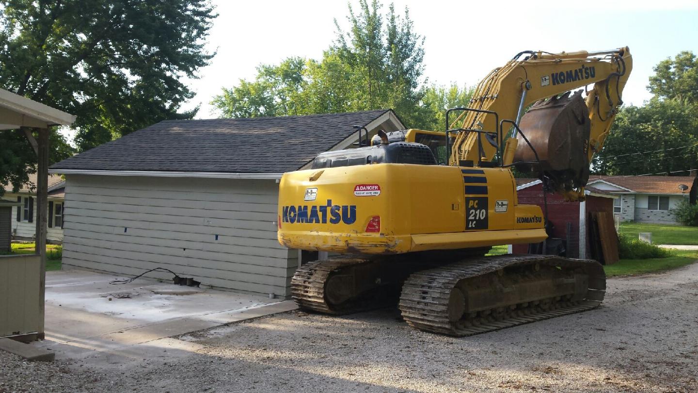 Picture of M&M's Kamatsu Excavator sizing up the garage it's about to tear down.