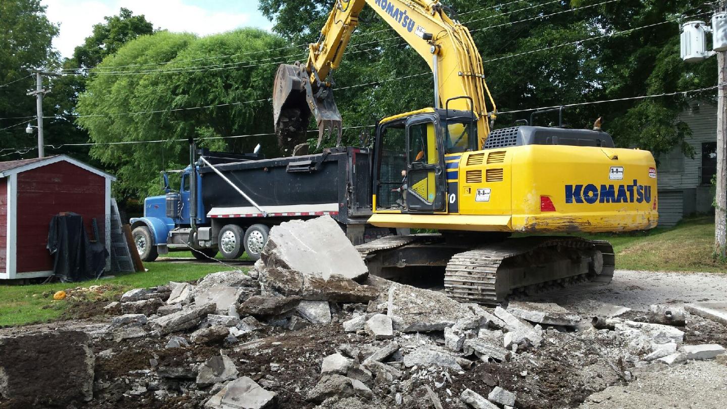 Komatsu Excavator loading a torn down house into dump trucks.