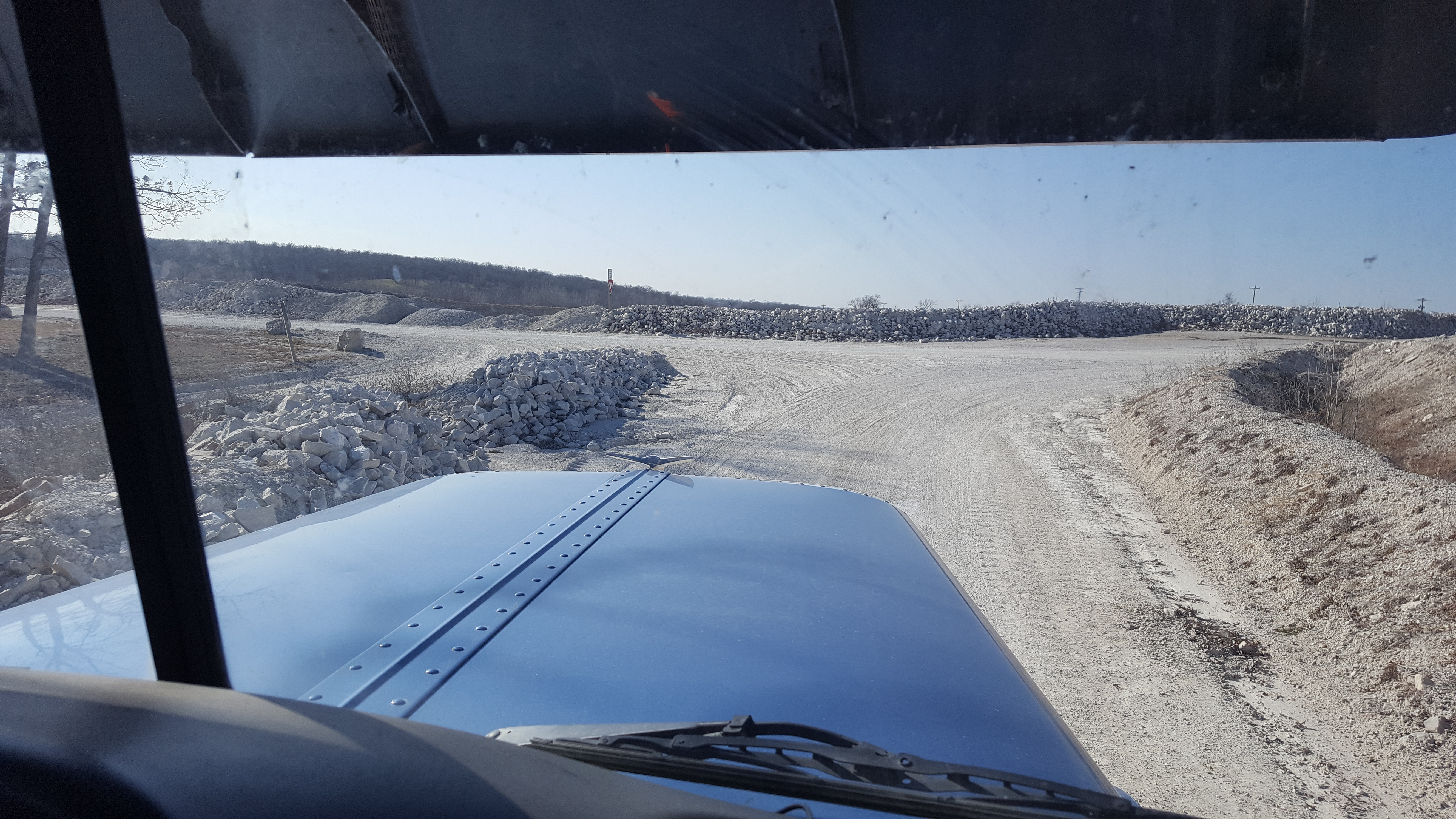 Picture from the inside of a truck looking out onto the hood and road ahead.